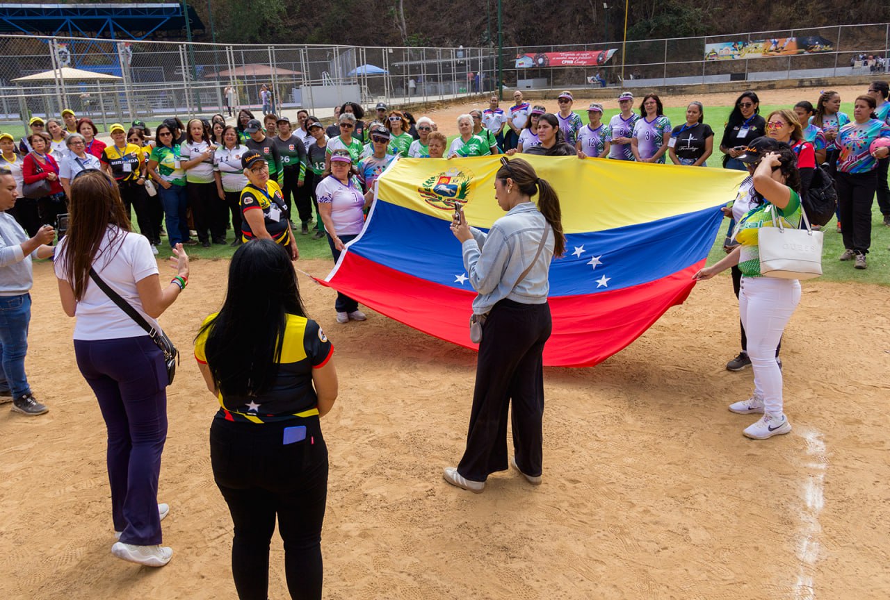 Participantes de una actividad de la Liga sostienen la bandera de Venezuela